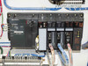 Mitsubishi MELSEC A-Series PLC rack installed in USHIO B0048 cabinet – A1SJHCPU, A1S62DA, two A1SX41-51 modules, A1SY81, and A1SJAR21 modules visible