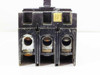 Unbranded 3-pole circuit breaker — bottom load-side lug terminals view with small yellow rating label partially visible