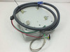 Bottom view of ADAM-4011 electrical enclosure showing four mounting feet, wiring conduit loop, and external cable with DB-9 connector
