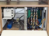 Interior cabinet of PWS P5NMS with lower bay open showing internal vacuum/pneumatic components (blue cylinder, solenoid assembly) and multi-slot electronics card cage with wiring harnesses