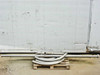 Stainless steel pipe lot on pallet — long straight section and curved bend sections visible outdoors