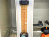 Close-up of rotameter variable area flowmeter inside enclosure showing dual scale and adjustment knob