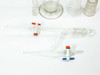 Lot of assorted laboratory glassware including tall graduated cylinder, adapter, buret with stopcocks, and small vials — overview