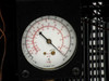 Internal refrigeration section of Thermonics T-2423 with compressor, refrigerant pressure gauge, condenser coil with fan guard, and copper refrigerant lines visible