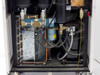 Internal view of rear side panel removed showing dual large black cylindrical accumulators/reservoirs, solenoid valve manifold, compressor, copper and flex refrigerant lines, and wiring