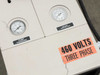 Top of AEC TDWF7M09S4 showing pump pressure gauge, return temperature gauge, and 460 Volts Three Phase warning label