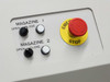 Side panel control panel showing MAGAZINE 1 OPEN/CLOSE switches, MAGAZINE 2 OPEN/CLOSE switches, and red mushroom-head EMERGENCY STOP button