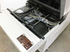 Interior detail showing control wiring, ribbon cables, actuator assembly, and a small accessory packet inside the machine cavity