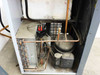 Atlas Copco FX7 A6 interior view with side panel removed — showing compressor, copper refrigerant tubing, heat exchanger coils, and capacitor