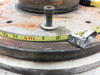 Top-down view of indexing drive table output flange with tape measure showing approximately 12-inch outer diameter and center bolt