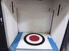 Interior dispensing bay of Corob AC10000 showing white-painted chamber with vertical guide rails and colorant target calibration bullseye plate taped to floor