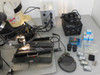Finetech Fineplacer system accessories laid out including Leica MZ6 microscope, Finetech Placer Control unit, two Euromex EK-1 fiber optic illuminators, TC-2000E converter, eyepieces, software CDs, and small accessory boxes