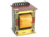 Industrial open-frame laminated core power transformer — front-left view showing wrapped bobbin winding, steel frame with surface oxidation, and red PCB terminal board on top