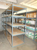 Multiple boltless steel rivet shelving units deployed in warehouse aisle loaded with boxes — side and context view