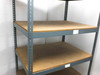 Boltless steel rivet shelving — close view of two middle shelves showing particle board surface and gray steel uprights
