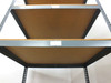 Boltless rivet shelving — low-angle upward view showing underside of particle board shelves and gray steel frame beams