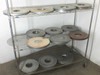 Lot of 13 Lapmaster 16-inch lapping and polishing plates on wire shelving rack — overview of all disks