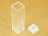 Brandtech polystyrene macro cuvette — single cuvette standing upright beside its stopper cap, showing 2 clear optical sides and 2 frosted sides