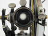 Close-up of theodolite telescope objective lens showing internal-focus design and brass housing