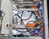 Internal lower chassis view showing orange-wrapped heating coil assembly, stainless manifold block with fittings, black high-voltage wiring, thermocouple wiring, and aluminum structural rails
