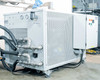 Rear of Opti Temp chiller unit showing stainless steel MNPT process pipe connections, insulated hoses, pressure gauges, and perforated steel cabinet