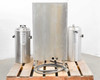 Fetco CBS-61H rear panel view showing stainless back panel with two Luxus TPD-30 dispensers flanking and power/water hose coiled on pallet