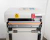Fuji VG-400C-10W sealing jaw area — orange heating element bar, jaw clamp brackets, and warning labels (Japanese and IEC hazard symbols)