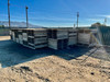 Multiple stacks of 48x48 treated wood pallets with plywood tops stored outdoors in a fenced yard