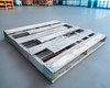 Single 48x48 wooden pallet laid flat on warehouse floor showing deck boards and stringers from above