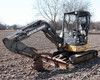 2013 John Deere 35G compact mini excavator with claw bucket and dozer blade in field — left front three-quarter view