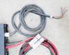Input power cable detail — heavy gray conduit cable coiled with bare wire ends and Anderson SB connector on output cable visible