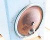 Close-up of hydraulic reservoir access port cover showing surface rust and paint loss around the oval cover plate