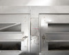 Close-up of fume hood center junction showing paint chipping, grease residue, and latch hardware between slotted vent panels
