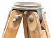 Close-up of cast metal tripod head platform with leg hinge knobs and wooden leg attachment joints visible