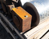 Detail view of yellow-painted hydraulic brake block with mounting bolt and rusty steel shaft end