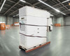Capstone C65 65kW microturbine generator on pallet in warehouse – full front-left view showing white multi-module enclosure