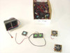 Assorted 12V DC CPU cooling fans in multiple sizes — box of fans in background with individual units laid out in foreground