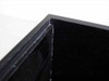 Close-up corner detail of black acrylic dry box showing panel joint construction and minor surface scratching