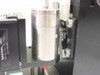 Close-up of cylindrical transducer module mounted in carriage clamp on Daedal assembly with Daedal Inc label visible in background