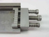 Close-up of IC test fixture jig showing adjustable clamping block with two knurled thumb screws and graduated scale