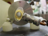 Close-up of Phase-R laser output aperture showing optical element and knurled coupling hardware with copper water cooling tube