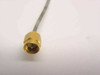 Close-up of straight SMA-Male connector on semi-rigid flexible coaxial cable showing gold-plated brass hex body and center pin