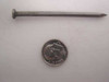 Single 8D 2.5-inch common steel wire nail shown next to a quarter for size reference