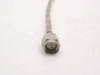 Close-up of SMA male straight connector on semi-rigid coax cable — silver hex body with gold center pin, braided outer jacket