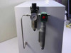 Close-up of pressure regulator with analog gauge and green solenoid valve with red actuator button mounted on container side panel
