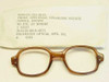 Rochester Optical military surplus eyeglass frame NSN 6540-01-153-3615 shown with original sleeve label listing NSN, cellulose acetate material, female brown, 46 eye 20 bridge, DLA contract number, and June 1991 date code