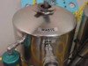 Close-up of stainless steel waste tank with WASTE and INLET labels and quick-disconnect inlet port fitting
