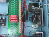 Interior detail showing green controller terminal board with Opto 22 style I/O connections, solid state relays, and regulated power supply mounted in right side of enclosure