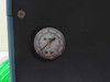 Front panel close-up of Watts dual-scale pressure gauge (bar and PSI) mounted in blue steel enclosure front panel
