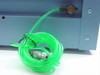 Green pneumatic tubing coiled beside blue enclosure with brass quick-connect fitting and inline valve, used for air/gas flow connections